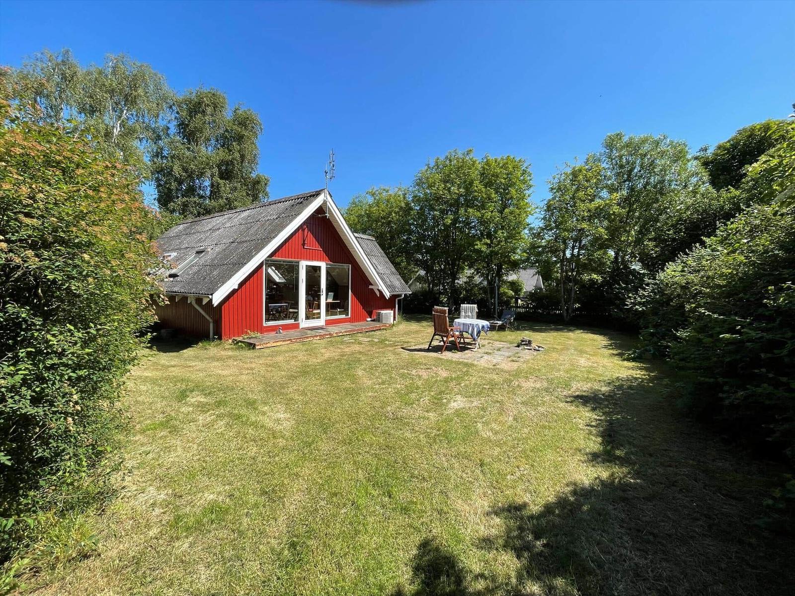 Rotes Haus mit Garten und Terrasse unter blauem Himmel