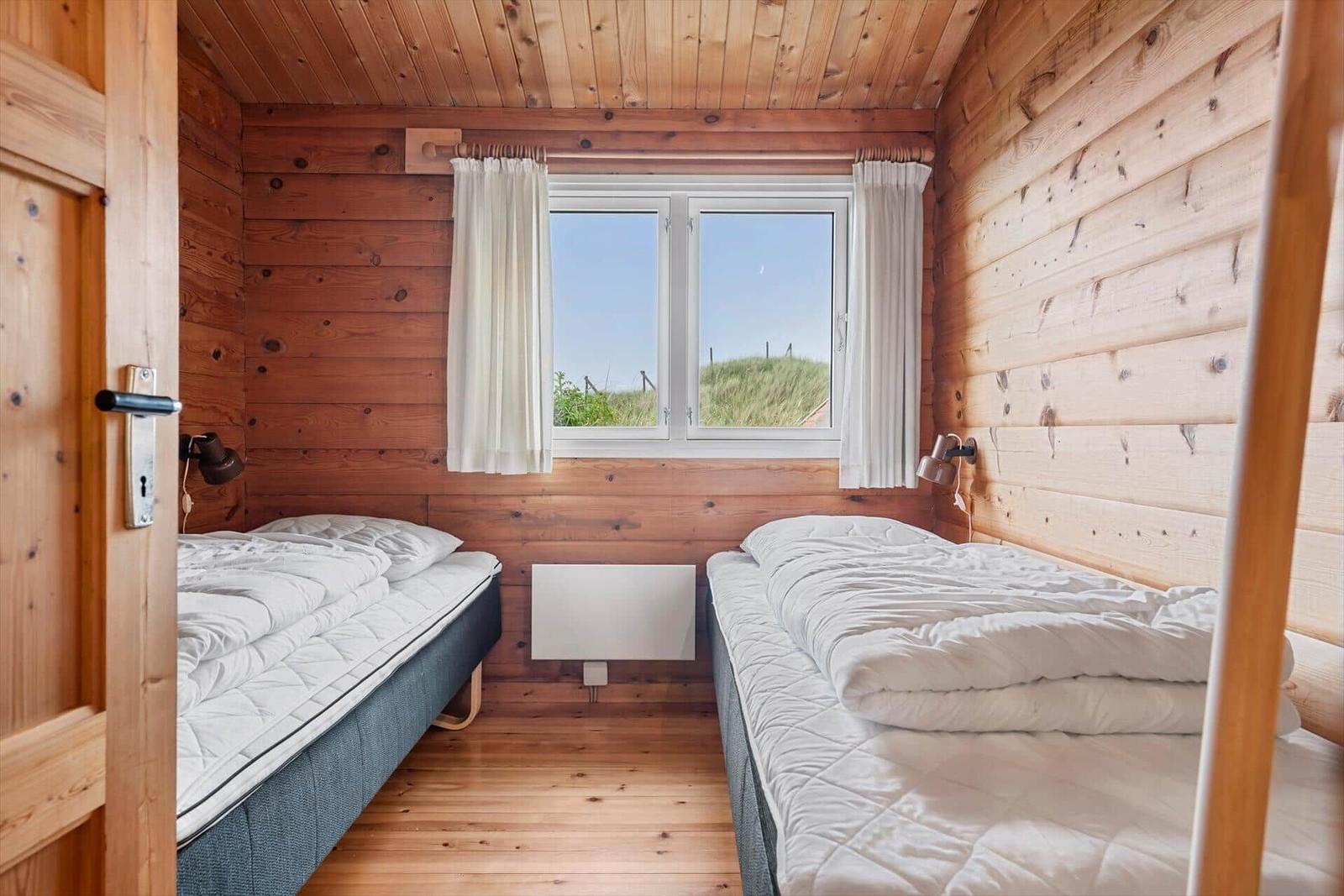 Zwei Betten in einem Holzhaus mit Fenster und Heizung.