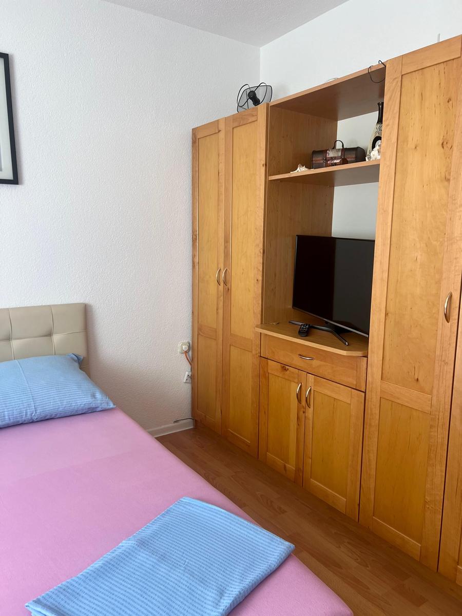 Schlafzimmer mit Bett, Holzschrank und Fernseher
