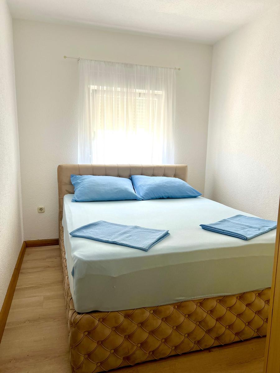 Schlafzimmer mit Bett, blauen Kissen und Vorhängen an Fenster