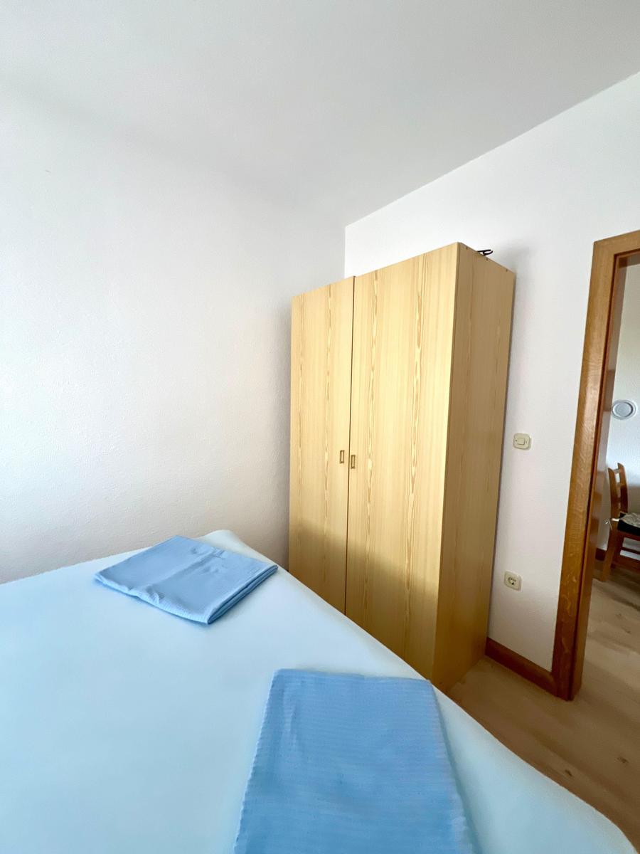 Schlafzimmer mit Bett, Kleiderkammer und Tür zum Flur.