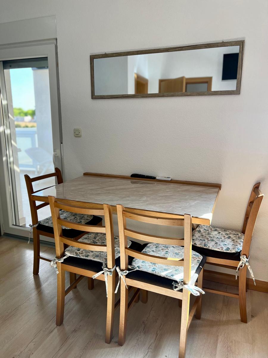 Esstisch mit vier Stühlen und Spiegel an der Wand.