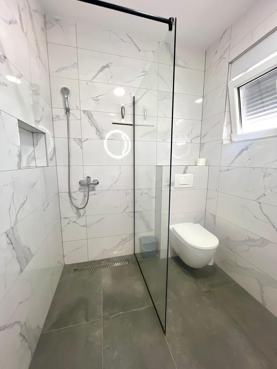 Badezimmer mit Dusche, Toilette und Fenster