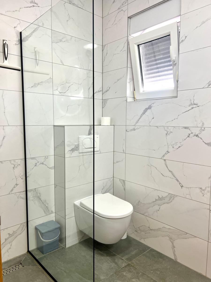 Badezimmer mit Dusche, Toilette und Fenster