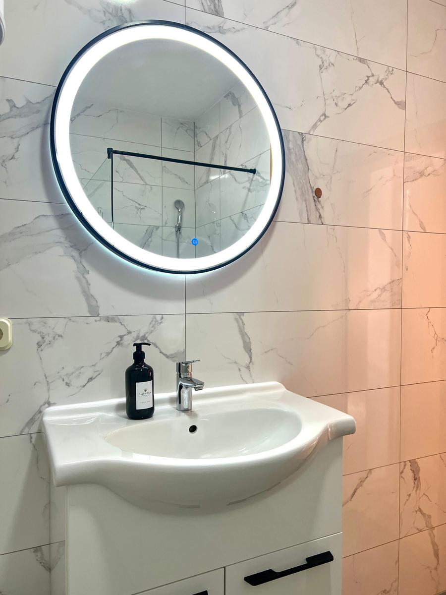 Badezimmer mit Waschbecken, Spiegel und Dusche