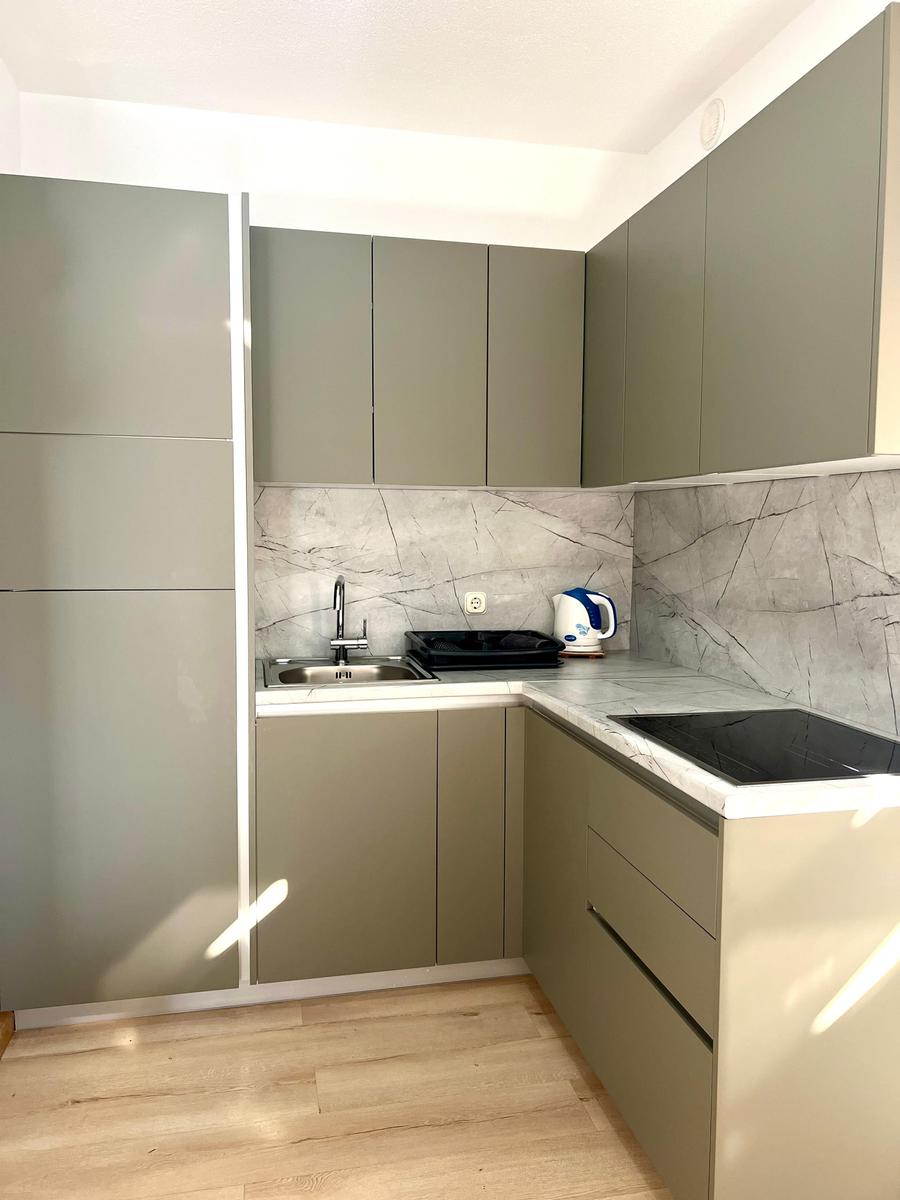 Küche mit grauen Schränken, Marmorwand und Holzboden