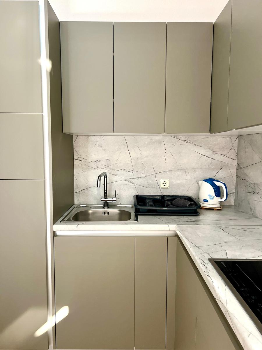 Küche mit grauen Schränken, Marmorarbeitsplatte und Edelstahlspüle.