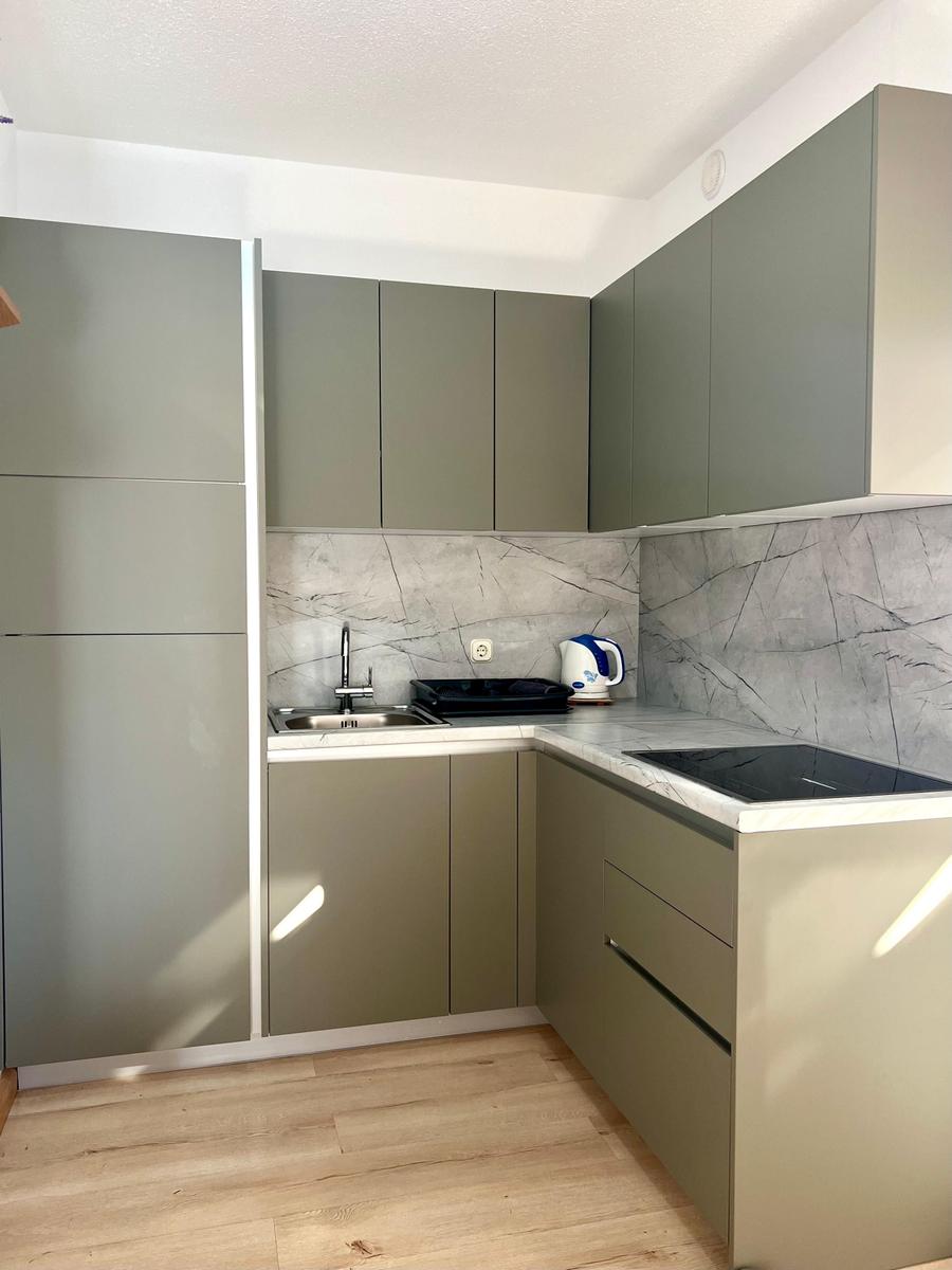 Küche mit grauen Schränken, Marmorwand und Edelstahlspüle.