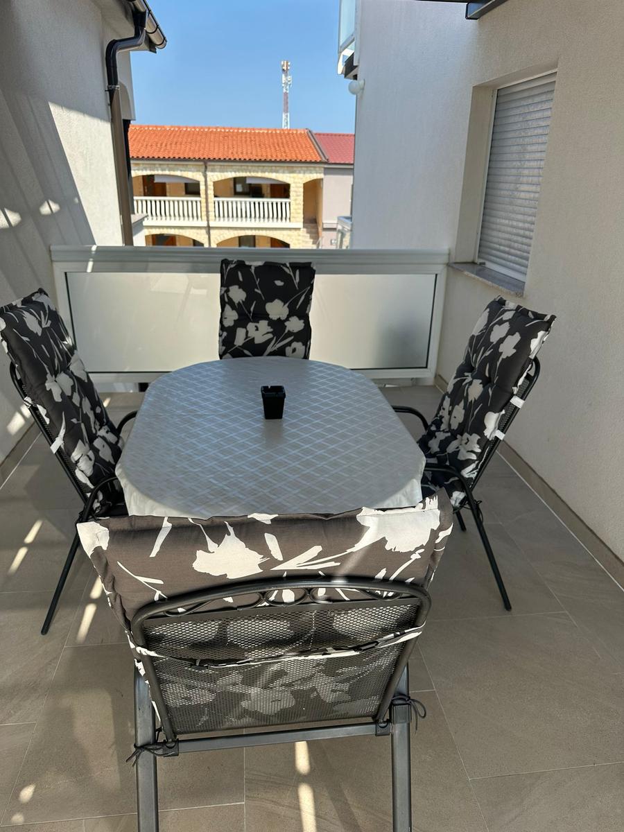 Terrasse mit Tisch und vier Stühlen mit floralen Bezügen.