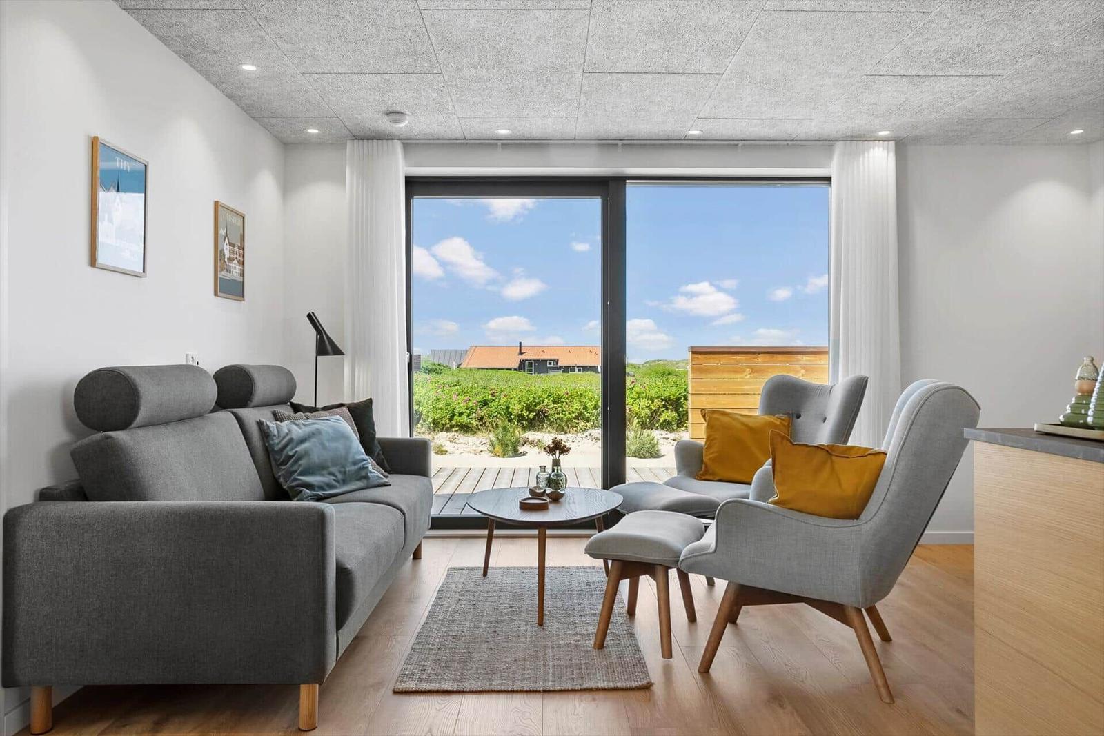 Wohnzimmer mit Sofa, Sesseln und Blick auf Garten