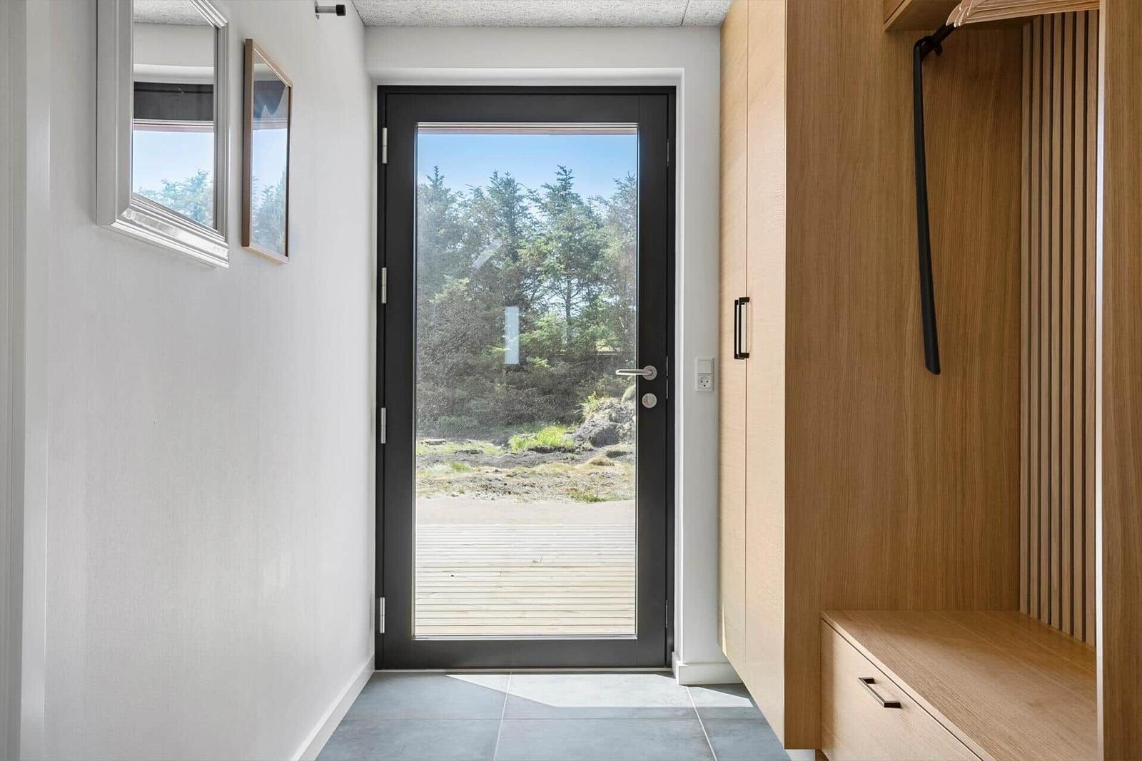 Eingangsbereich mit Holzschrank und Glastür zum Außenbereich.