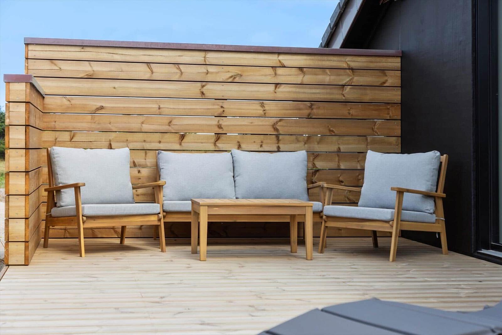 Terrasse mit Holzgeländer, Sitzgruppe und Tisch.