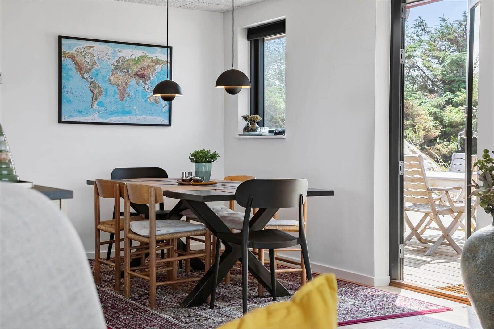 Esszimmer mit Tisch, Stühlen und Weltkarte an der Wand. Durchgang zur Terrasse.