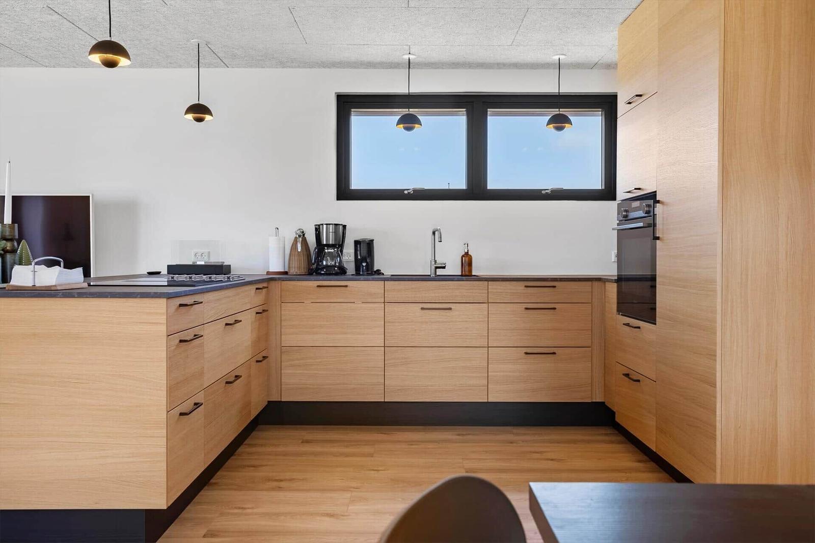Moderne Küche mit Holzschränken, Arbeitsplatte und Fenster.
