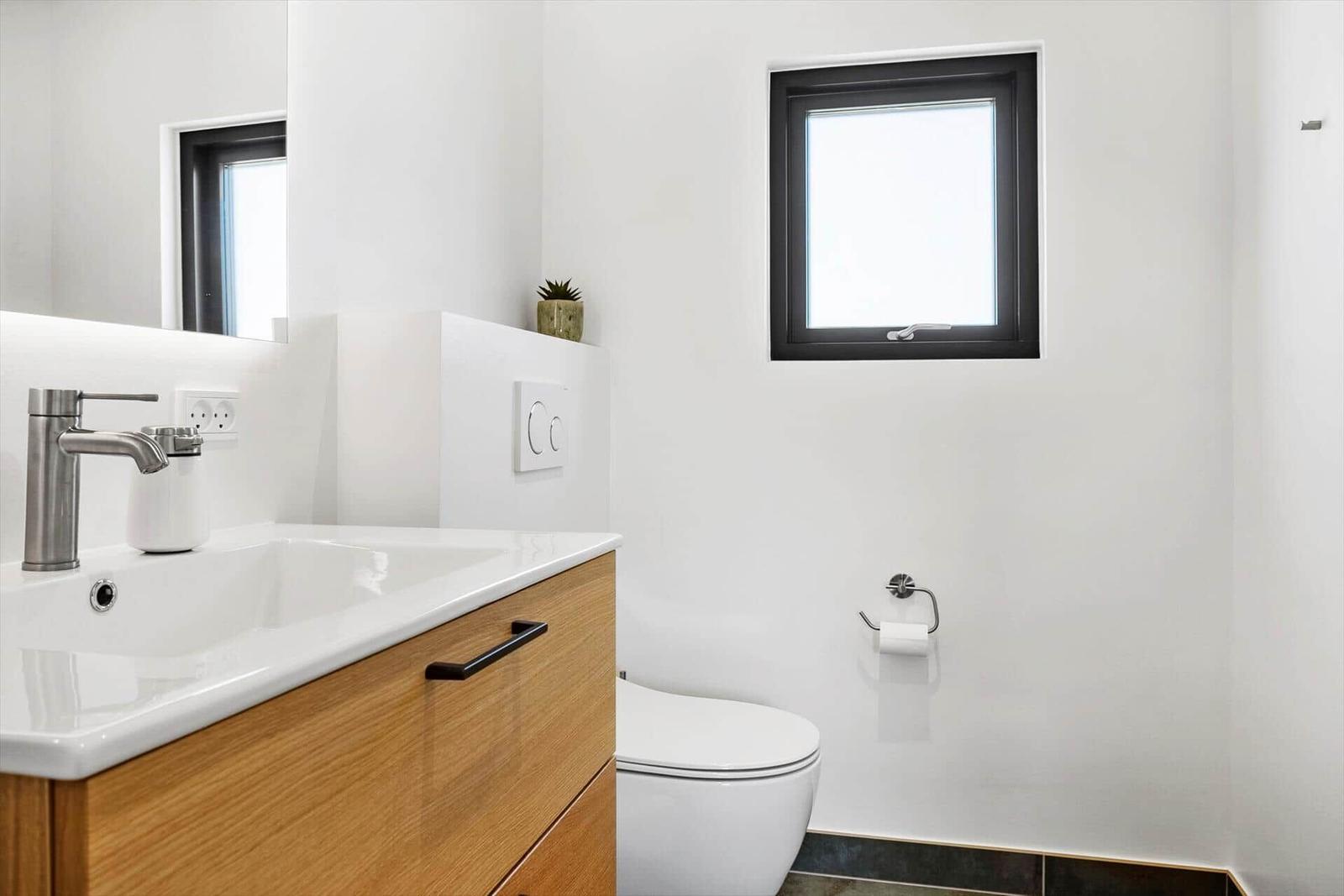 Badezimmer mit Waschbecken, Toilette und Fenster.