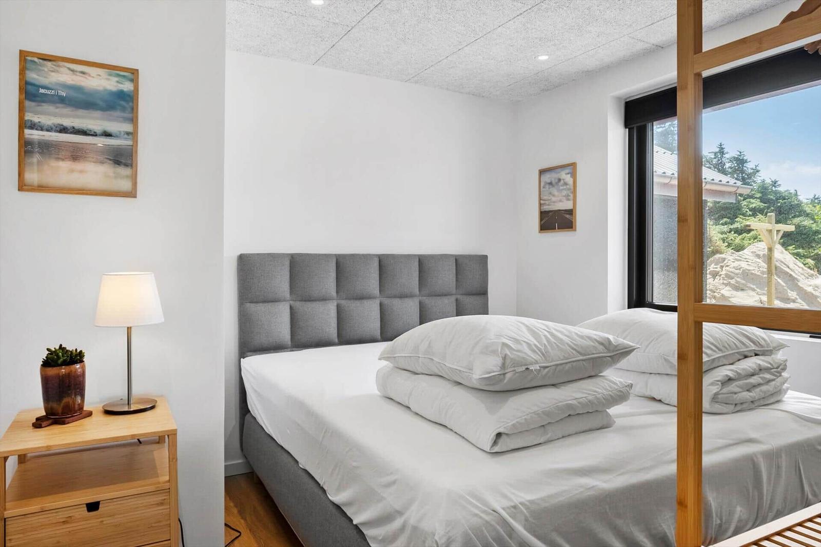 Schlafzimmer mit Bett, Nachttisch und Fensterblick.