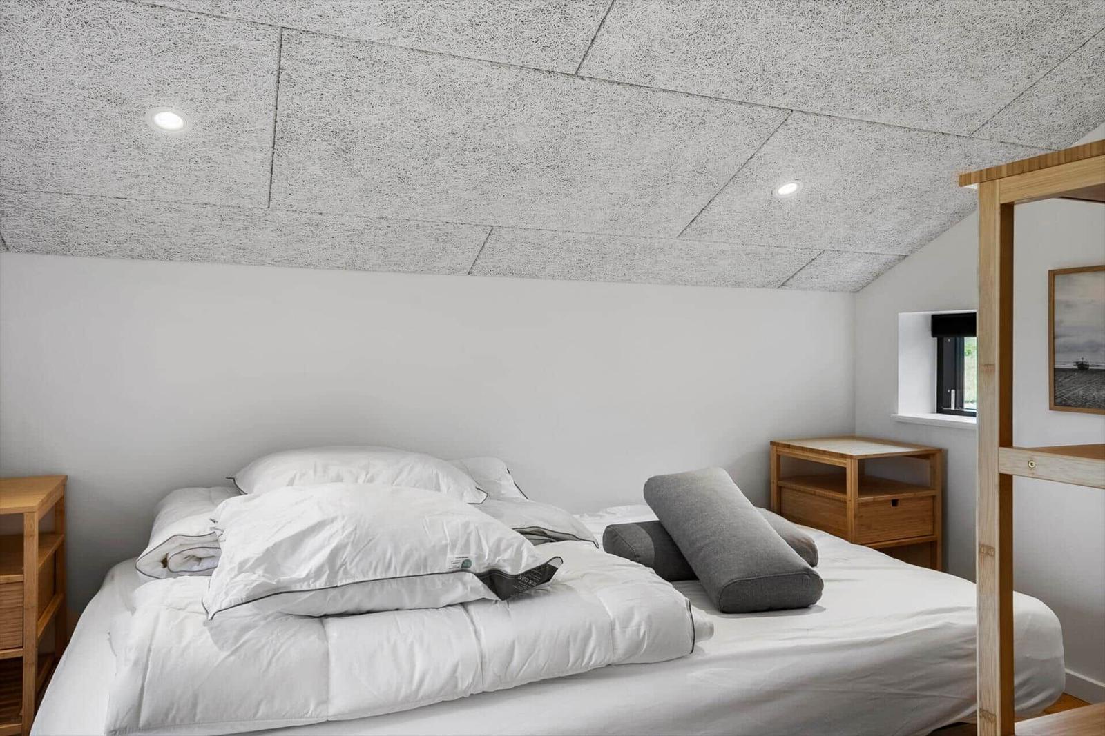 Schlafzimmer mit Bett, Nachttisch und Fenster. Decke aus Steinplatten.