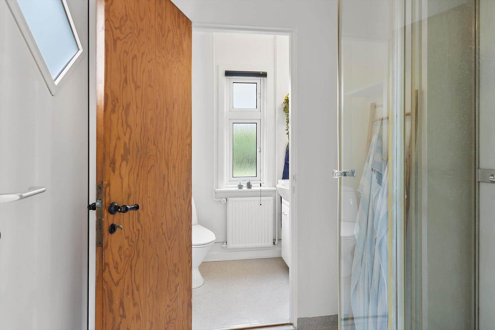 Bathroom with shower, toilet, and window.