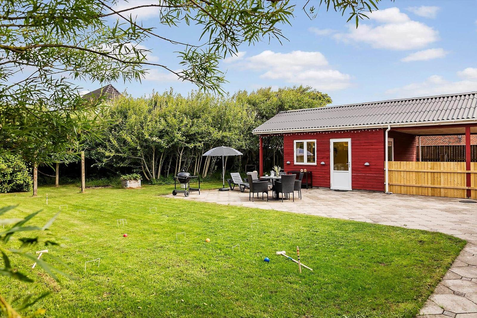 Red garden house with terrace, grill, and croquet lawn.
