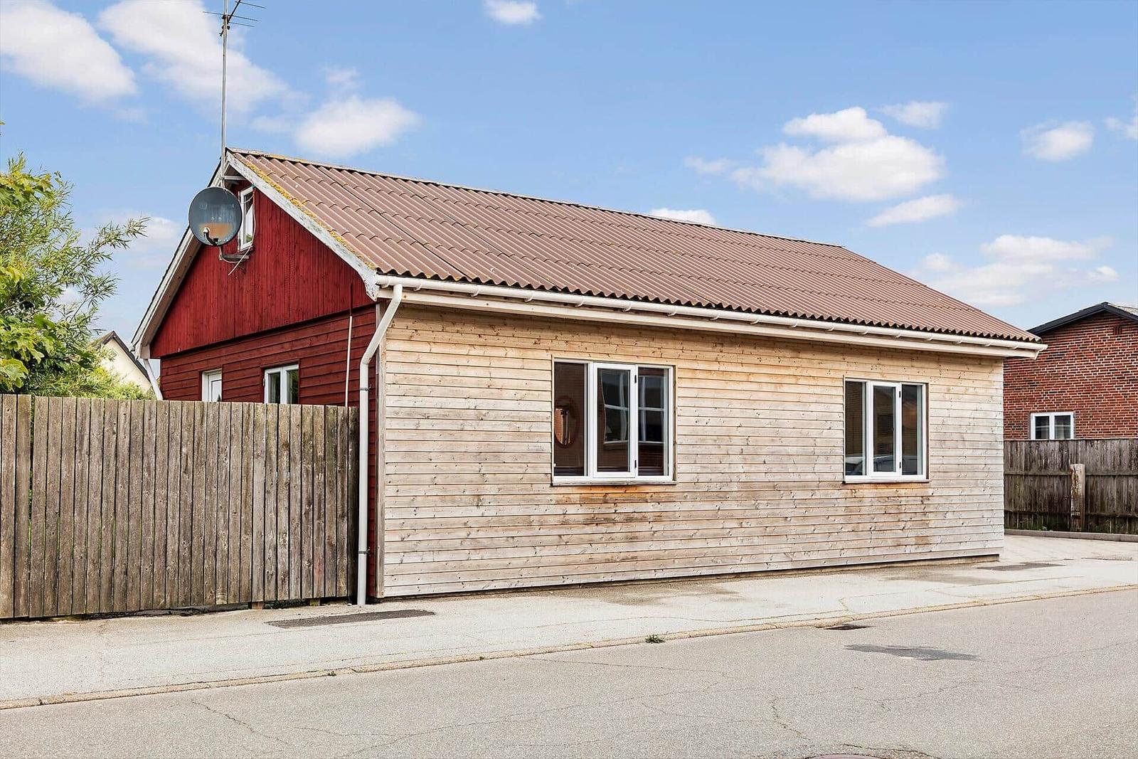 A house with wooden siding and a red gable roof. Windows and antenna are visible.