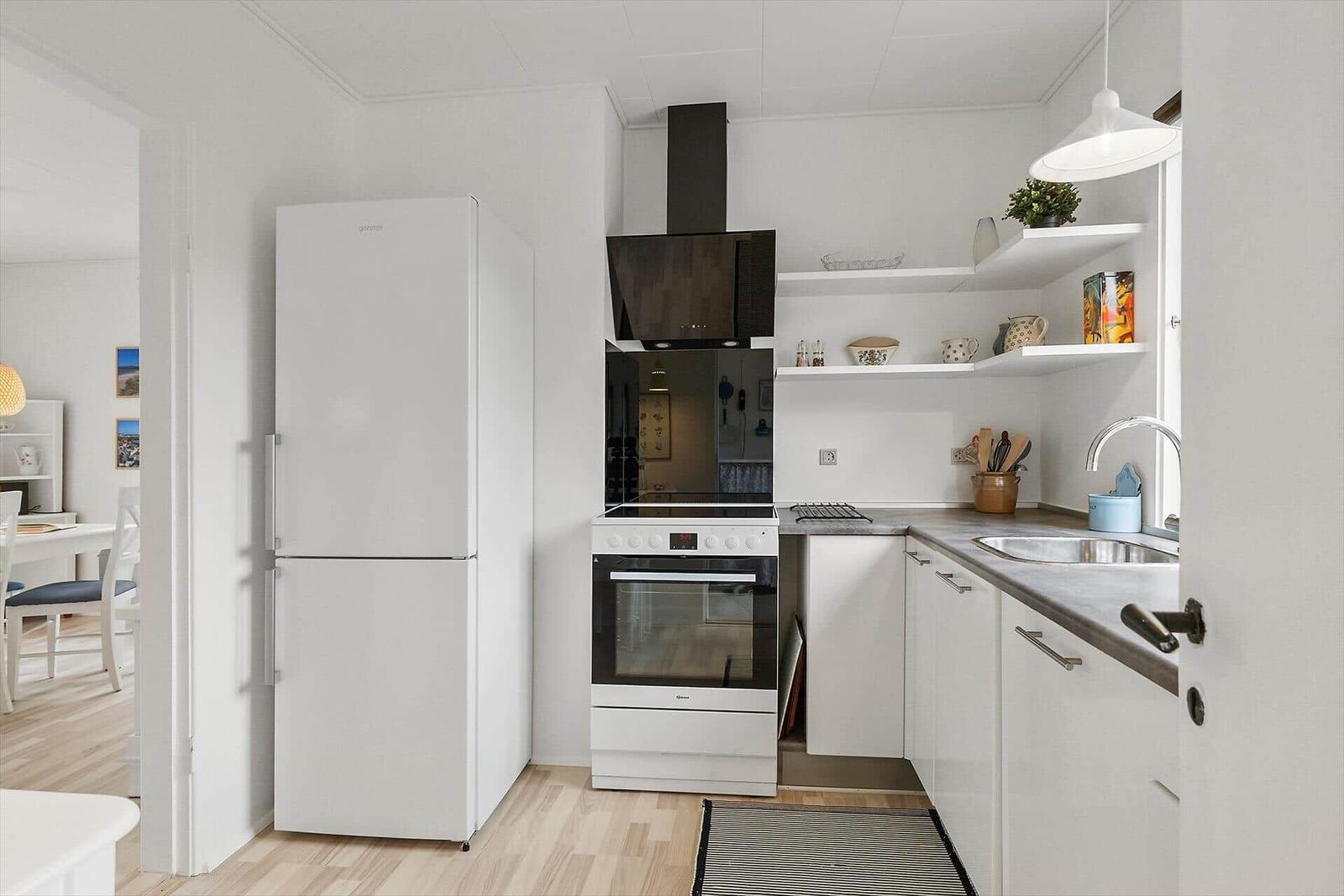 Kitchen with refrigerator, stove, and sink. White cabinets and countertop.