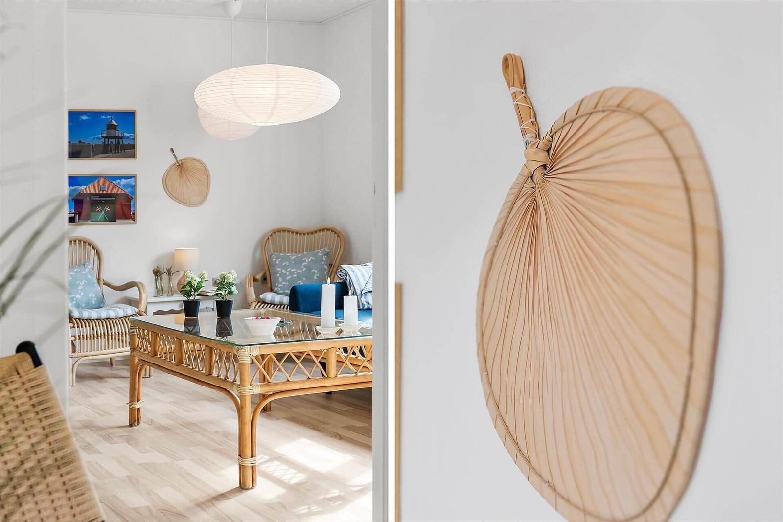 Living room with rattan furniture and glass table. Wall decor with fan.