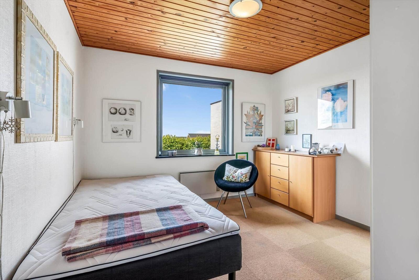 Schlafzimmer mit Bett, Fenster, Schrank und Stuhl.