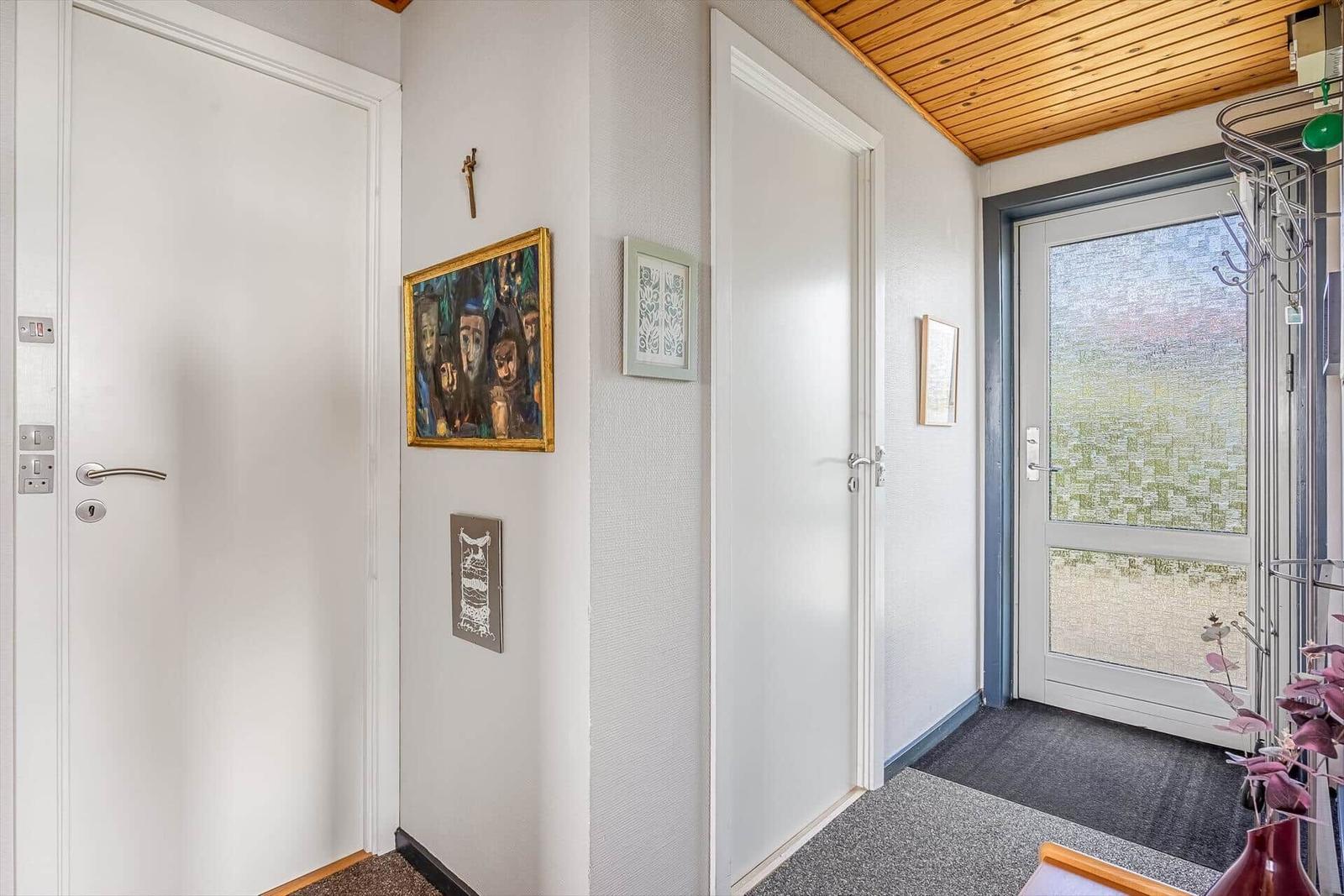 Flur mit zwei Türen, Wandbildern und Holzdecke.