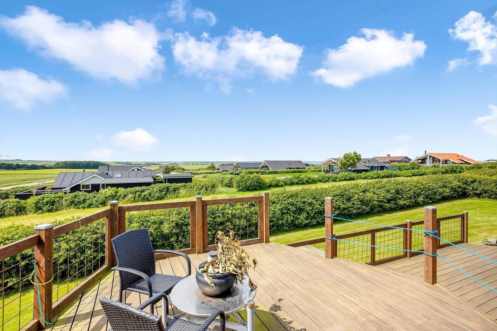 Terrasse mit Sitzgelegenheit und Blick auf grüne Landschaft und Häuser.