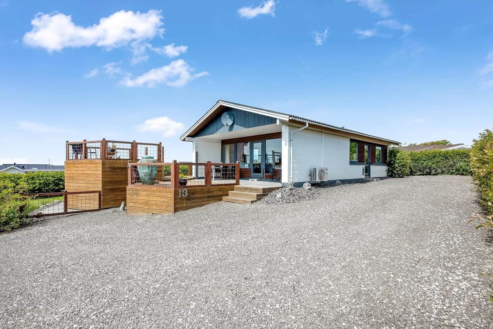 Moderne Villa mit Terrasse und Kiesweg. Hausnummer 13 sichtbar.