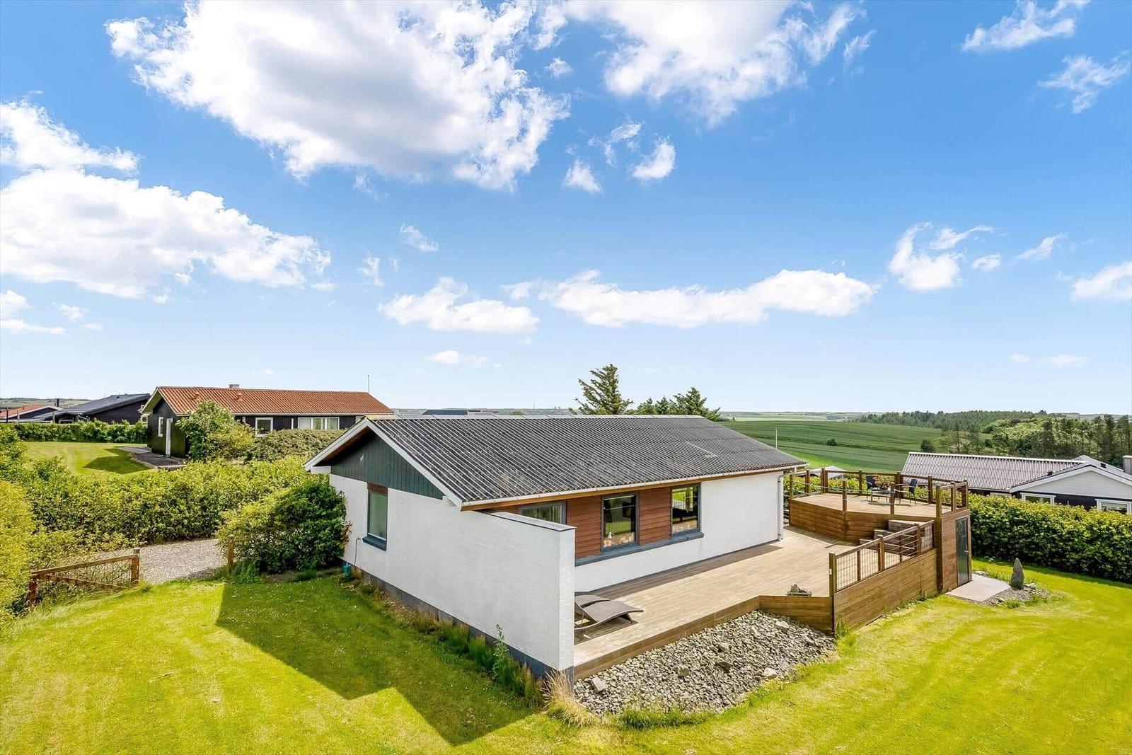Moderne Villa mit Terrasse und Garten. Blick auf Felder und Bäume.