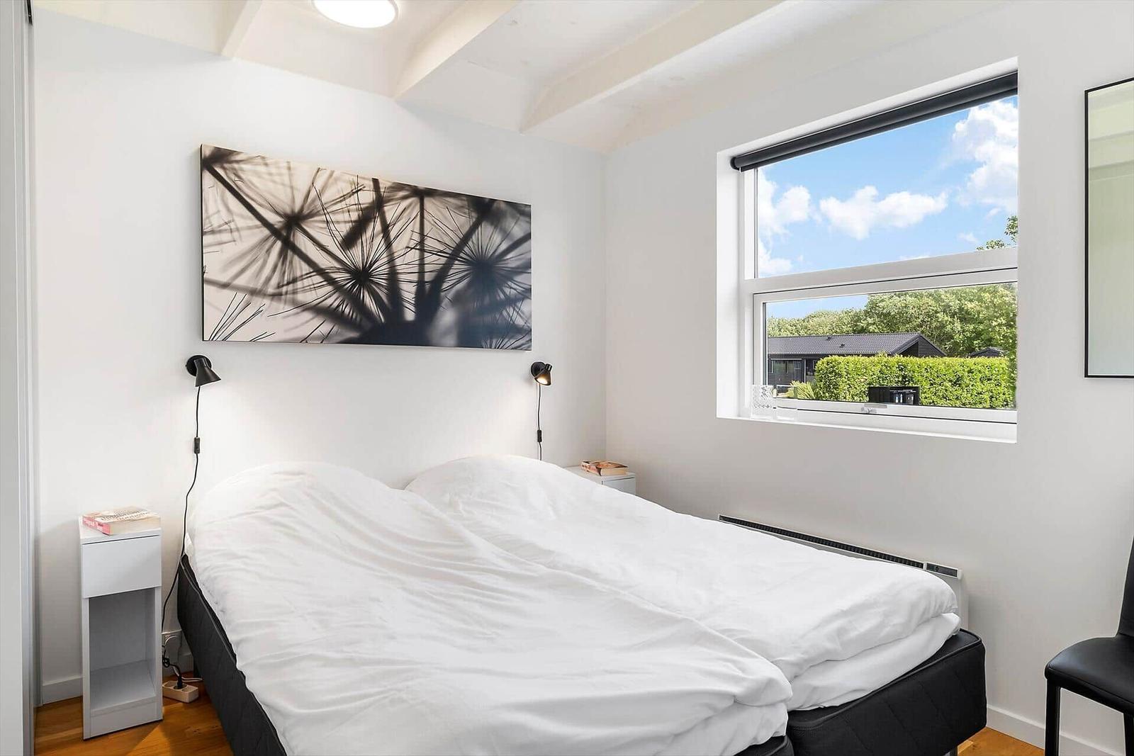 Schlafzimmer mit Doppelbett, Fenster und Wandbild.