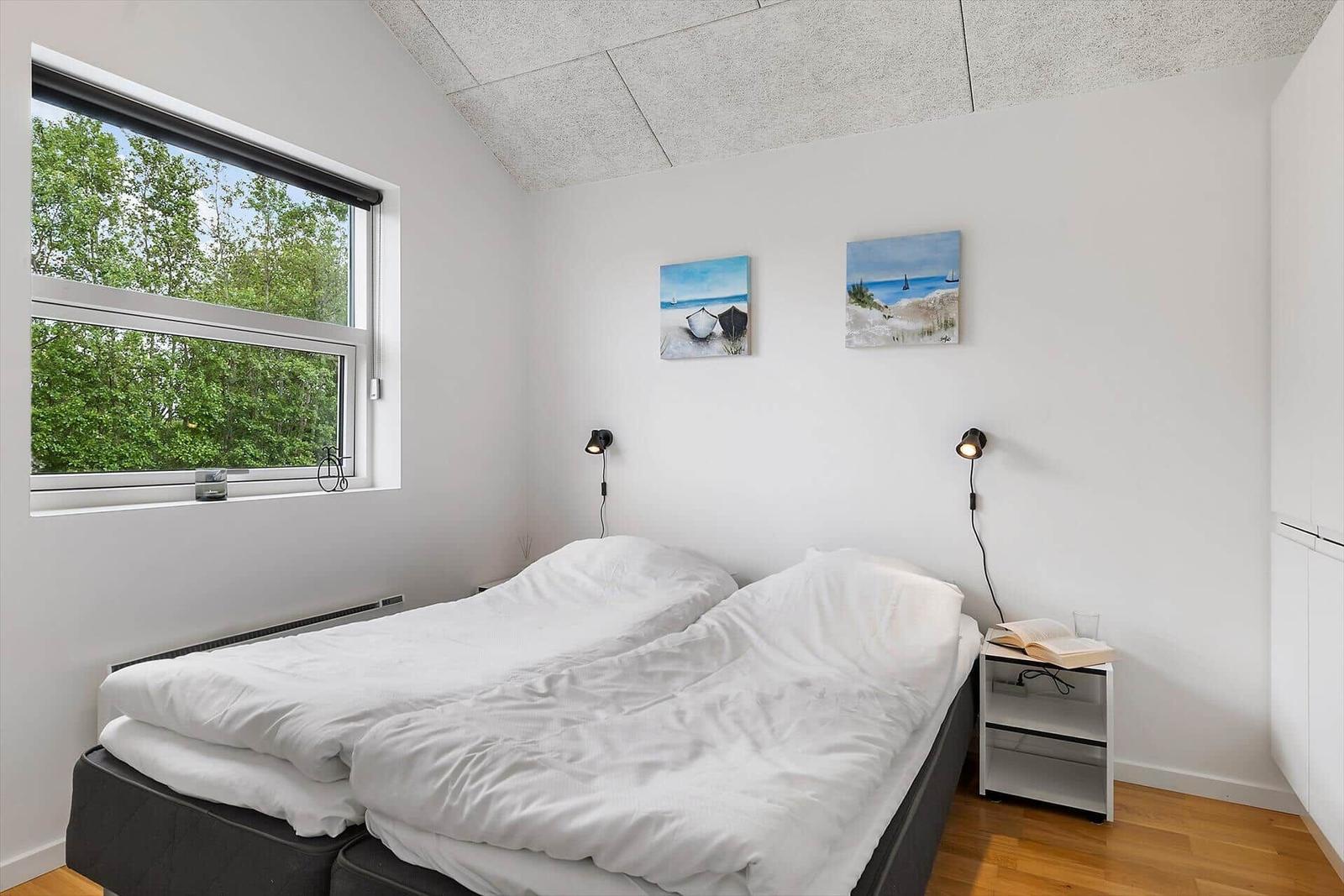 Schlafzimmer mit Doppelbett, Fenster und zwei Wandbildern