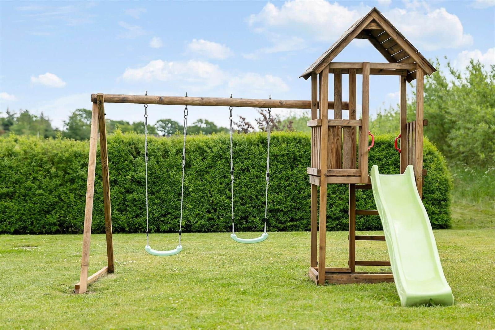 Holzspielplatz mit Schaukel und Rutsche im Garten