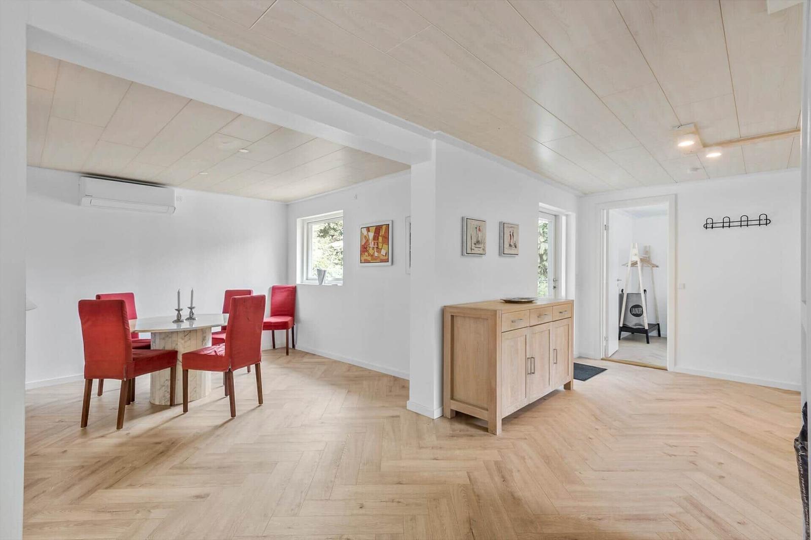 Esszimmer mit roten Stühlen und Holzboden. Flur mit Sideboard und Bildern an der Wand.