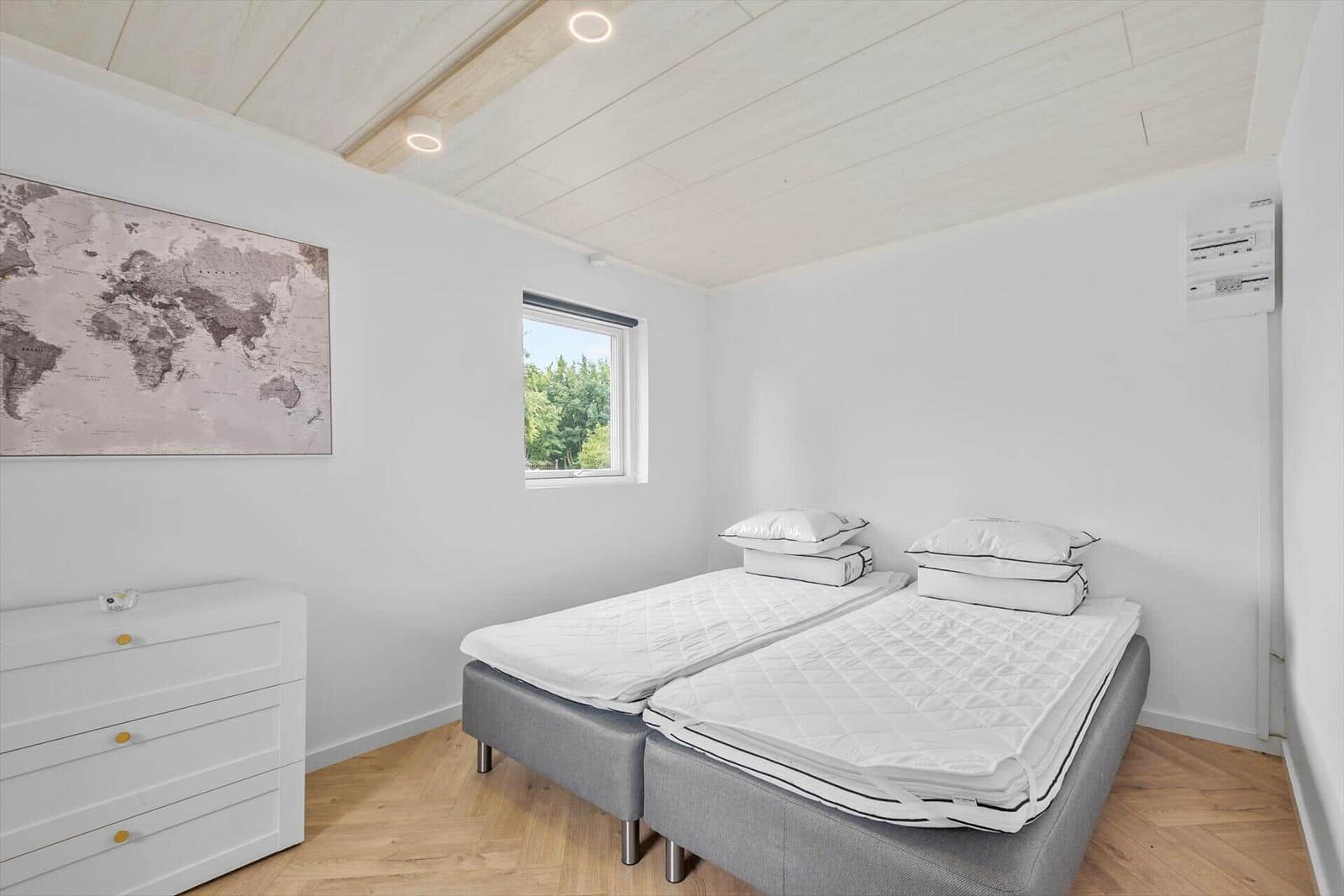 Zimmer mit zwei Schlafplätzen, Fenster und Weltkarte an der Wand.