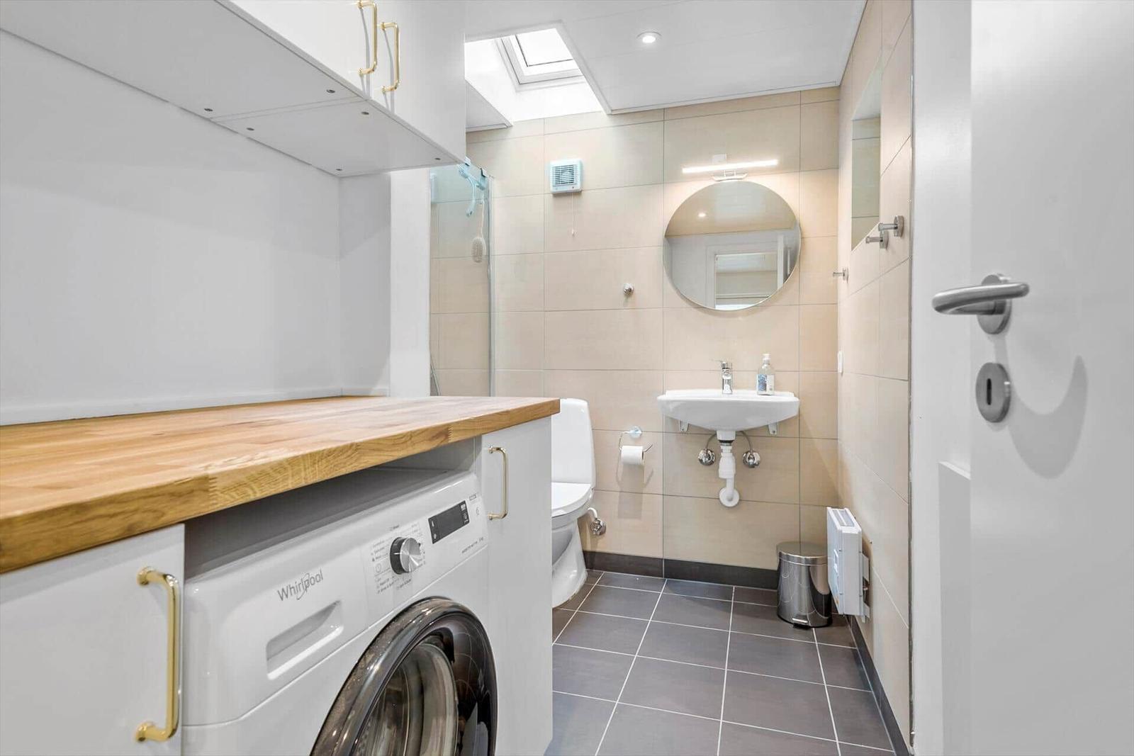 Badezimmer mit Waschmaschine, WC und Waschbecken unter Dachschrägen.