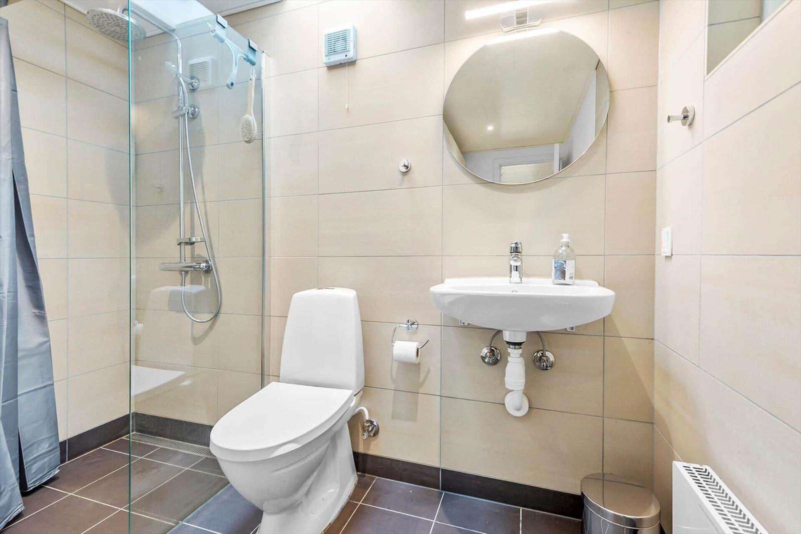 Badezimmer mit Dusche, Toilette und Waschbecken.