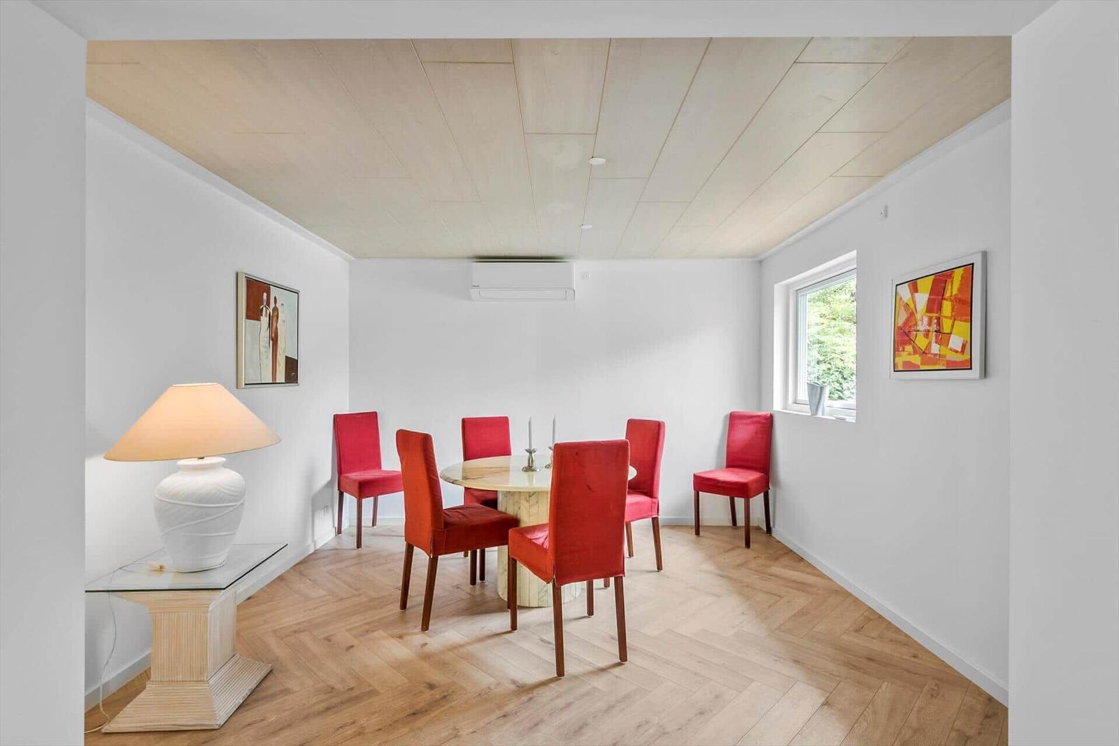 Esszimmer mit runden Tisch, roten Stühlen und Holzboden