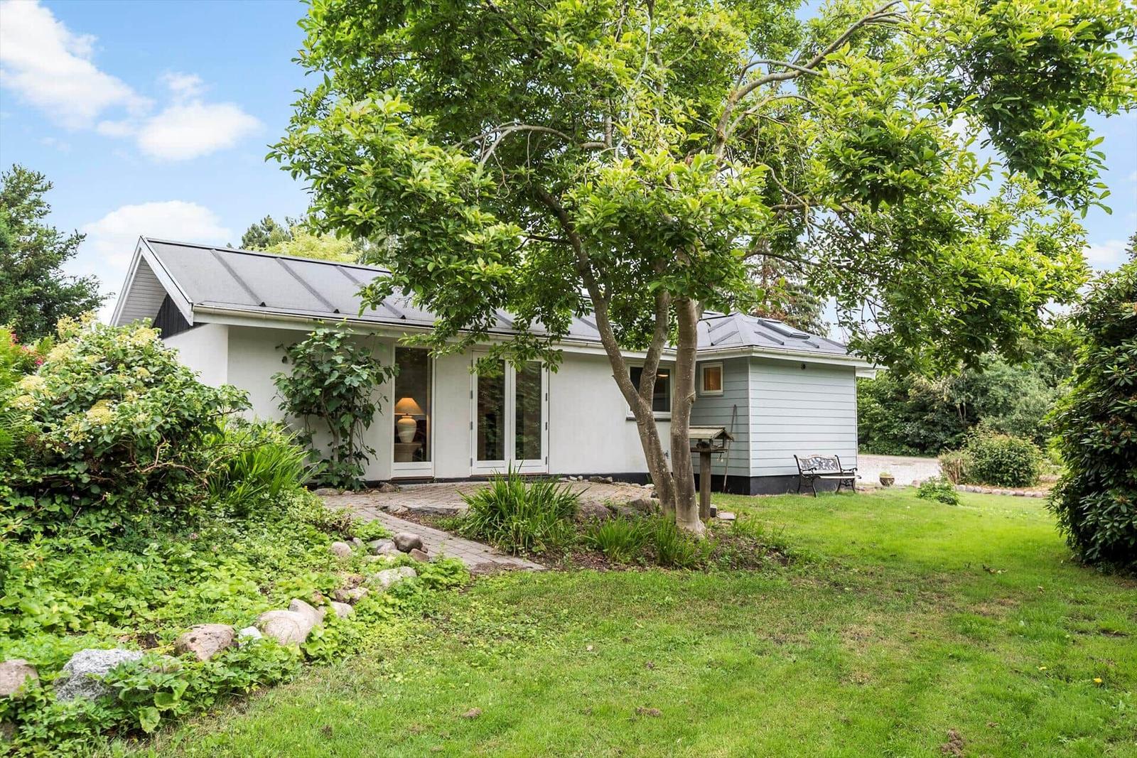 Ein Haus mit Garten, Bäumen und einer Bank im Freien.