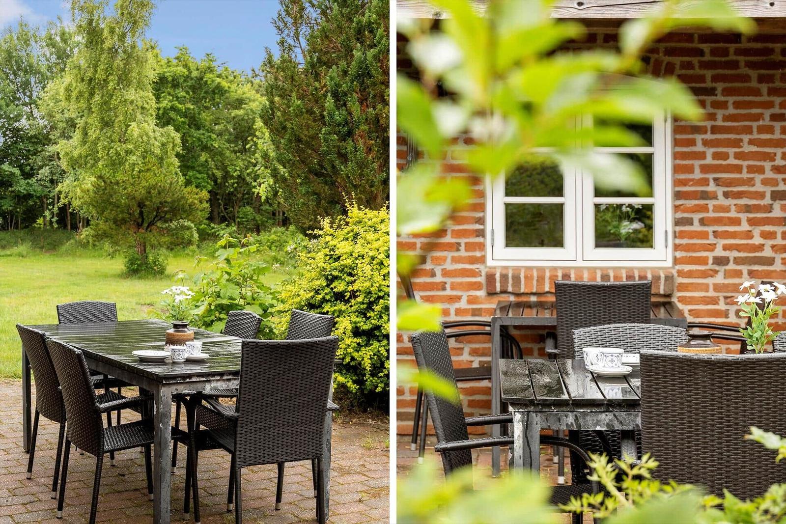 Terrasse mit Tisch und Stühlen vor einem Backsteinhaus mit Fenster.