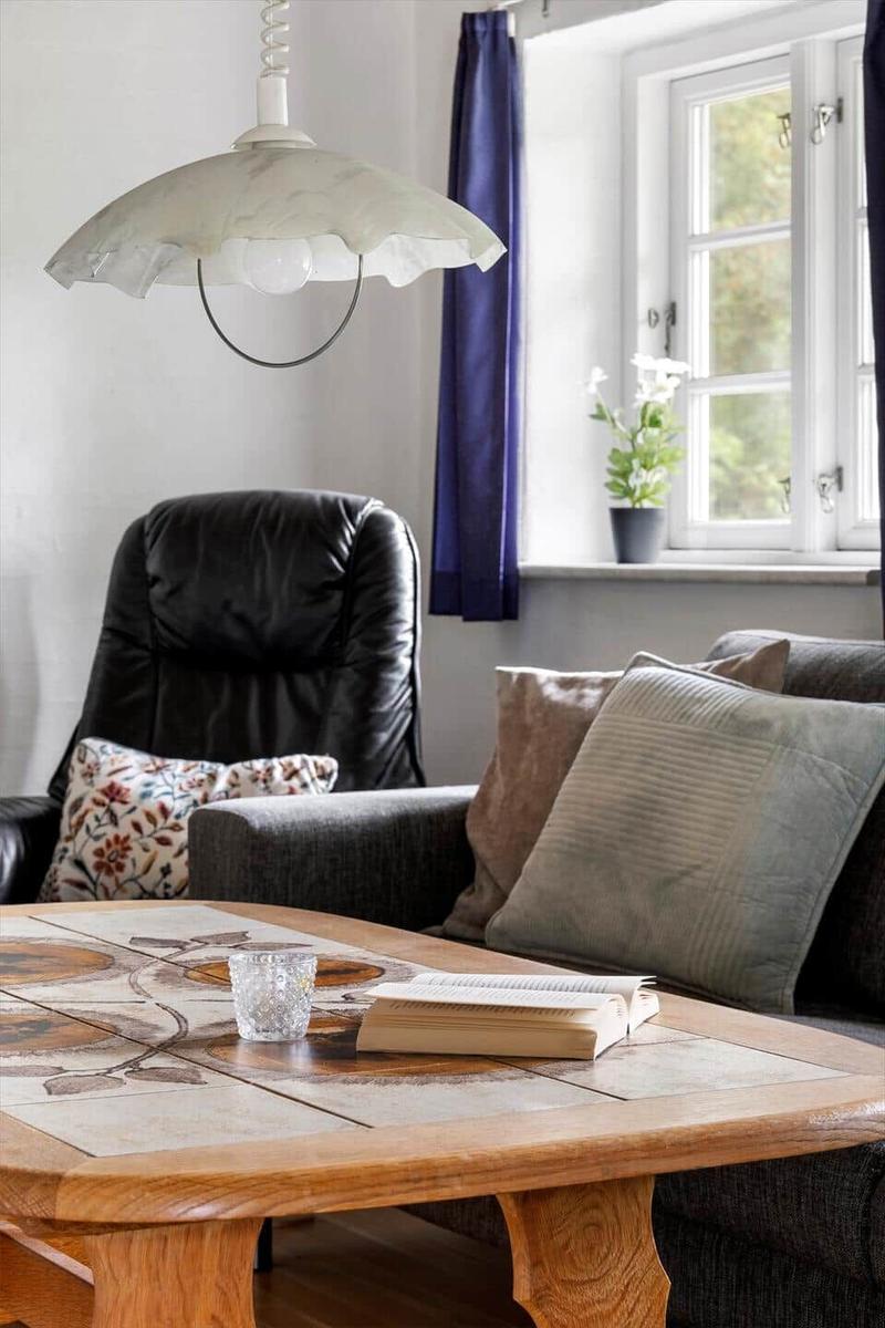 Ein Wohnzimmer mit Sofa, Sessel, Tisch und Fenster.