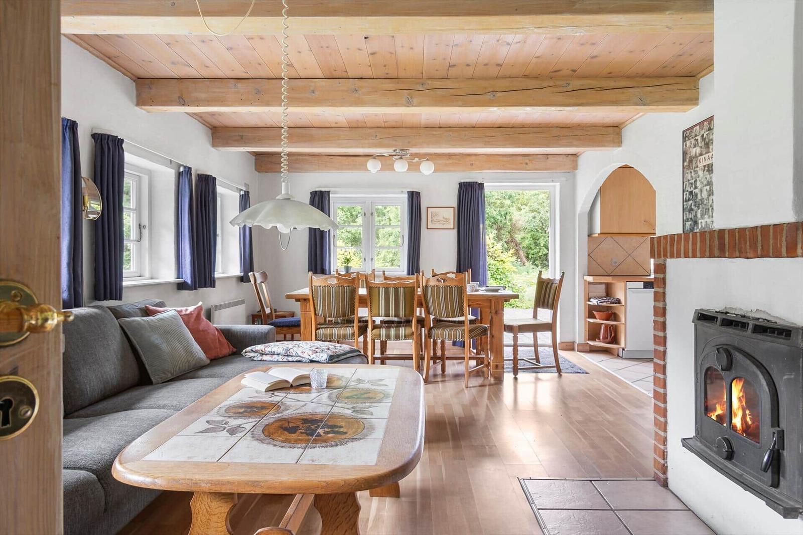 Wohn- und Essbereich mit Holzdecke, Kamin und Essgruppe.