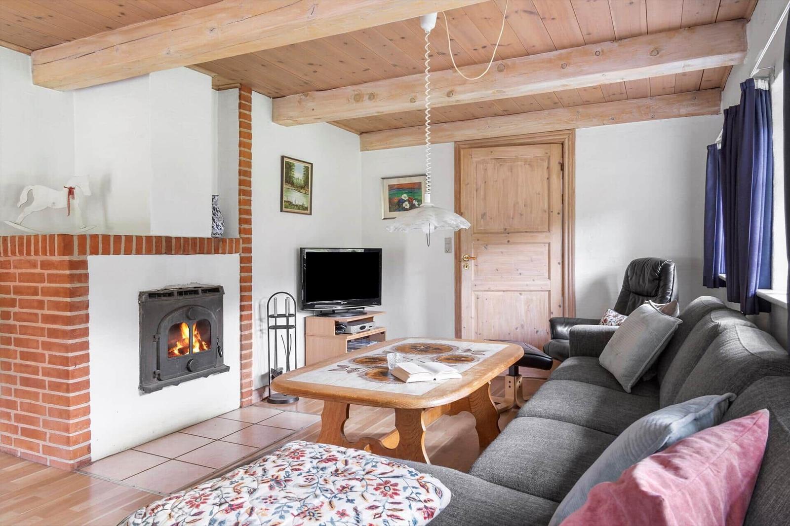 Wohnzimmer mit Kamin, Sofa, Tisch und Fernseher.