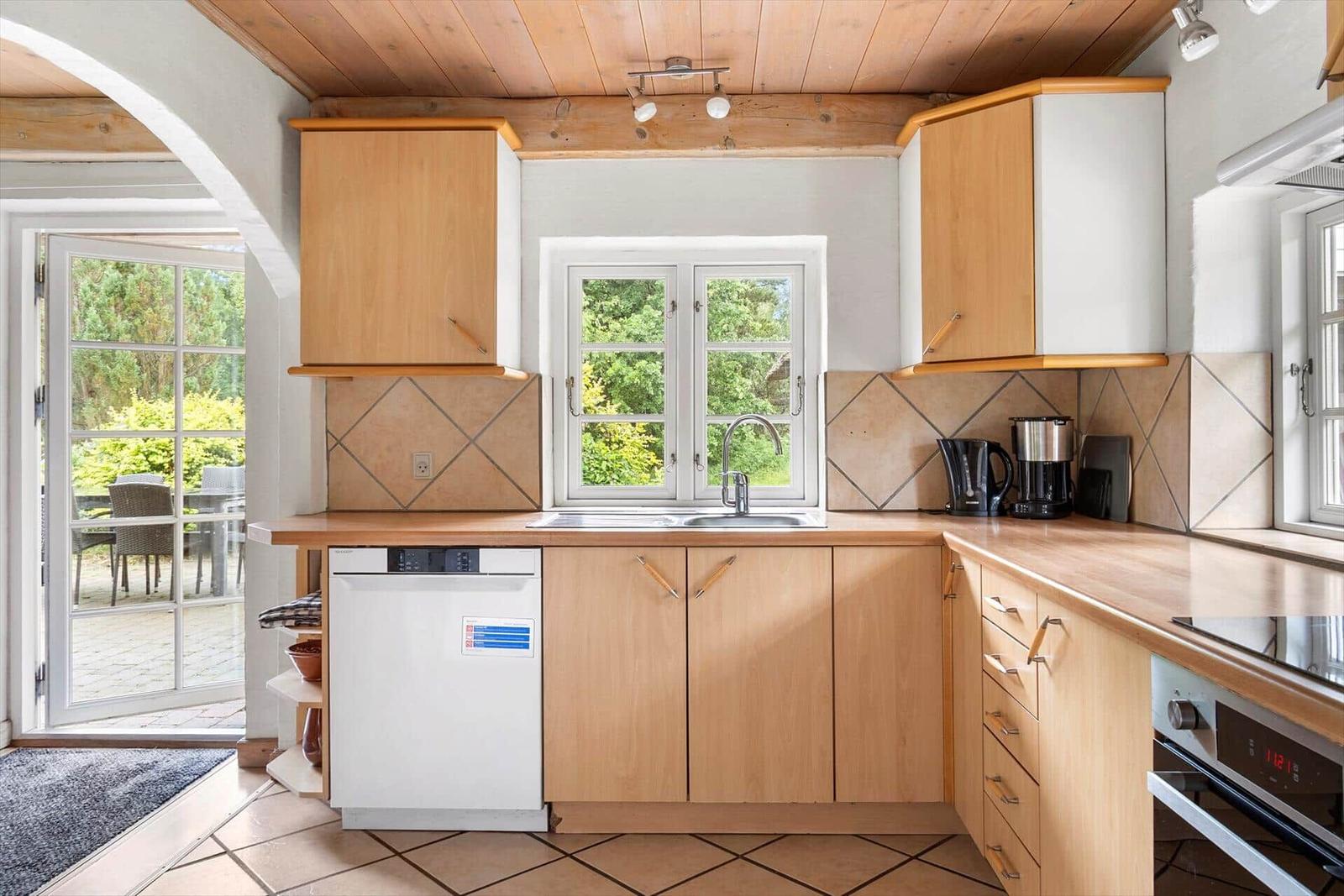 Küche mit Holzschränken, Spüle und Blick auf Garten