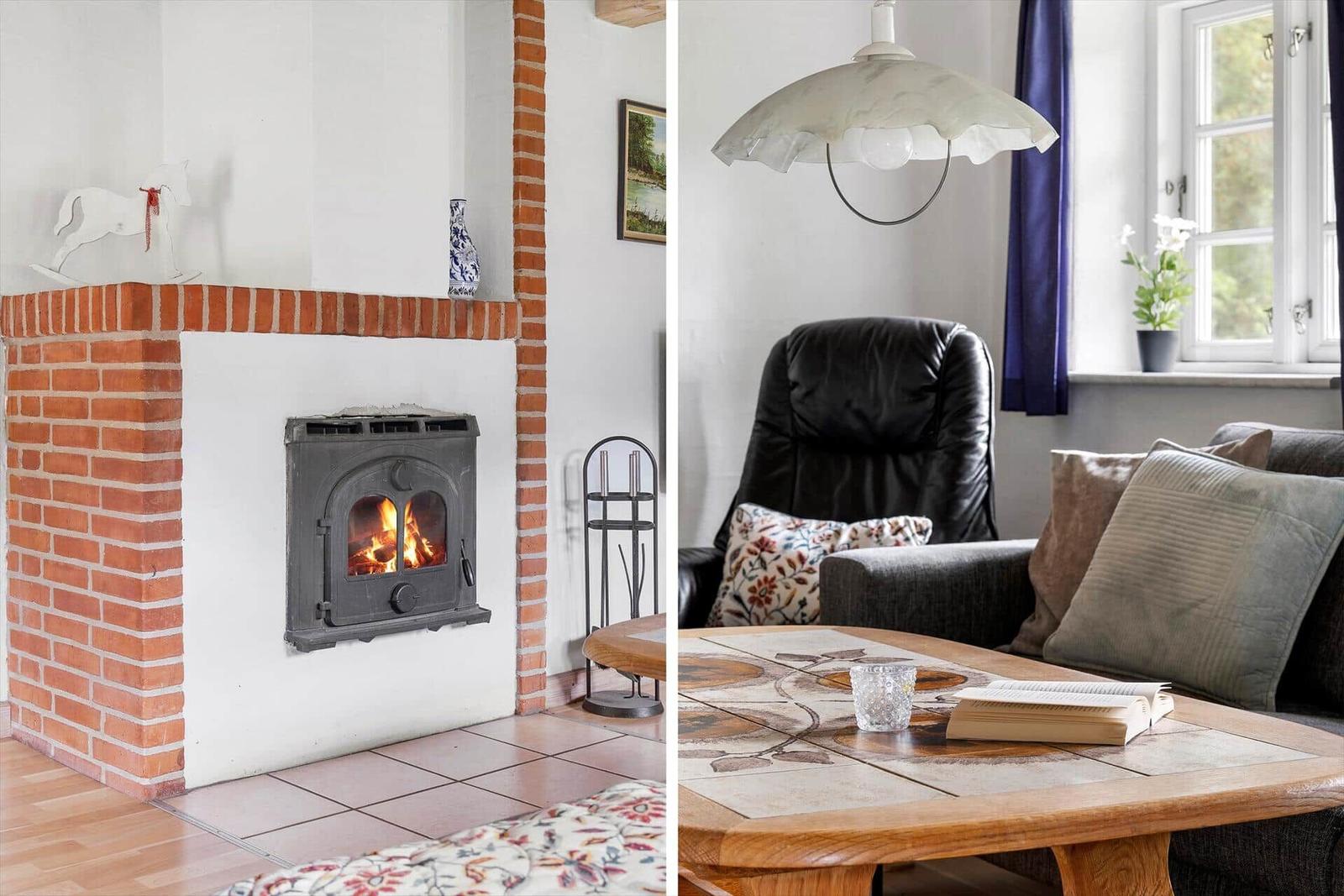 Kamin mit brennendem Holzofen und gemütlicher Sitzgruppe mit Couch und Tisch.