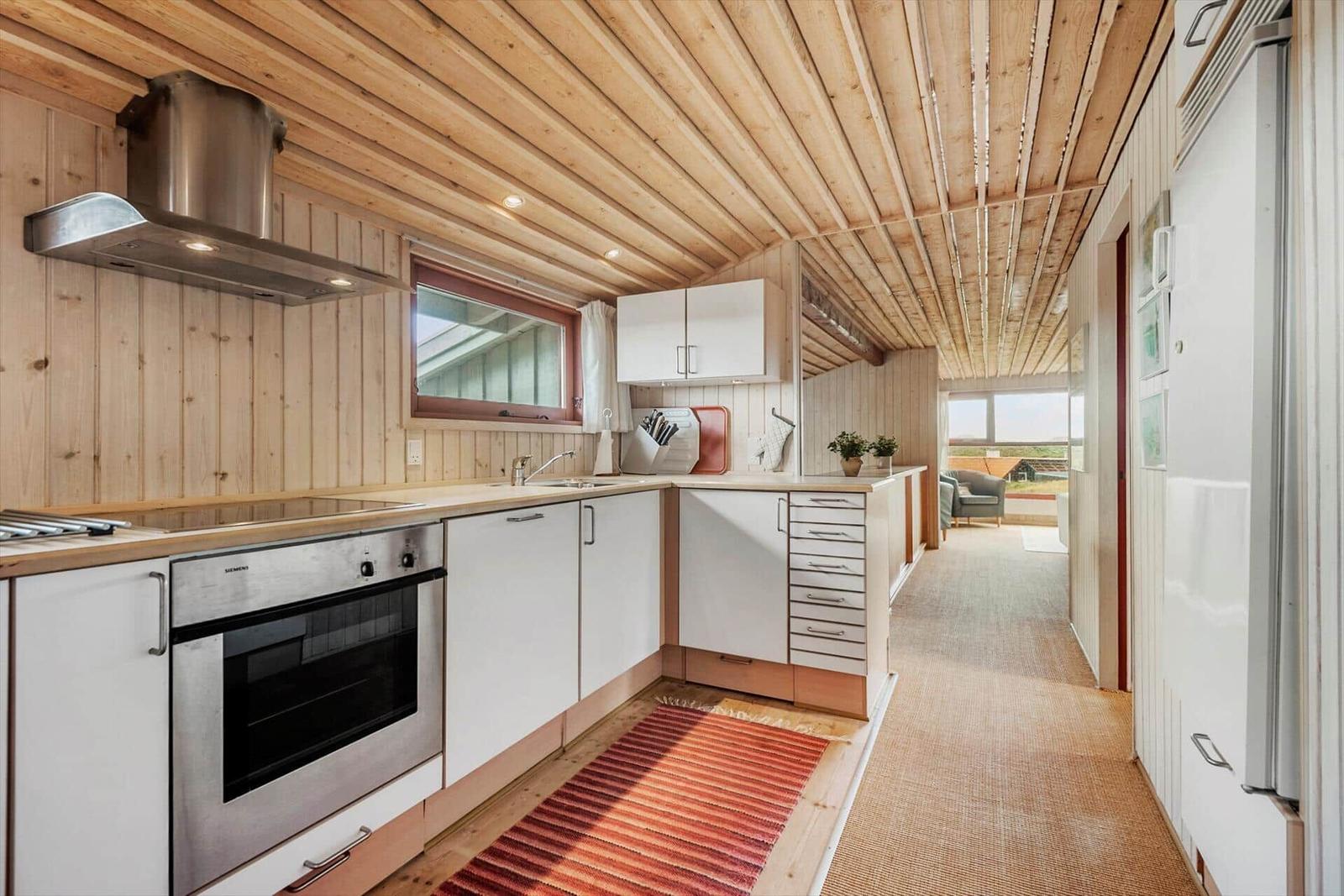 Küche mit Holzwand, Edelstahlherd und rotem Teppich