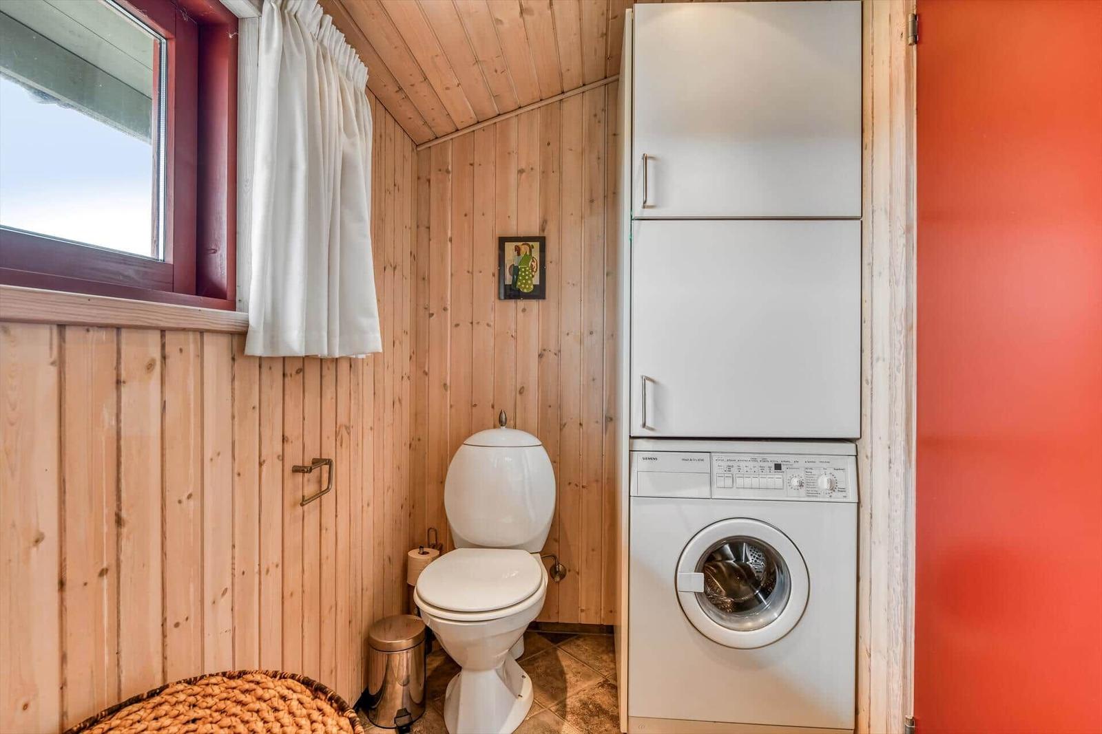 Badezimmer mit Toilette, Waschmaschine und Fenster.