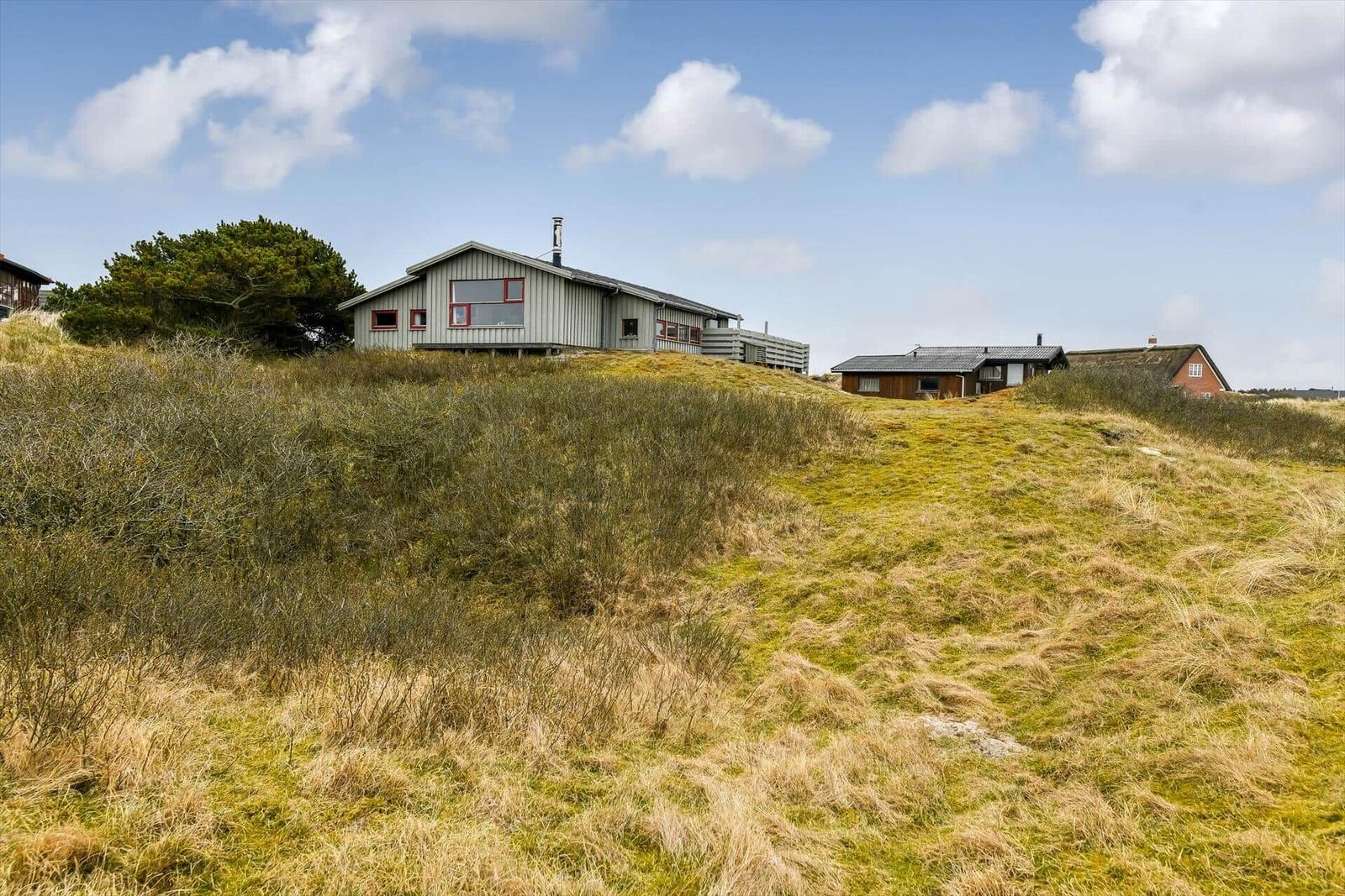 Haus auf grüner Anhöhe mit Blick auf den Himmel