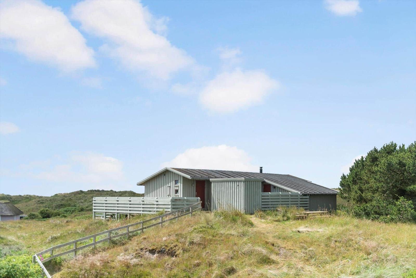 Moderne Strandhütte mit Terrasse und Blick auf die Dünen.
